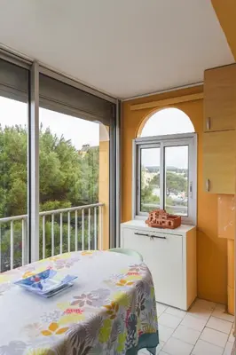 a bedroom with a bed and a balcony with windows at Le Nautilus in Gruissan