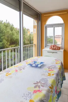 a bedroom with a bed and a balcony with windows at Le Nautilus in Gruissan