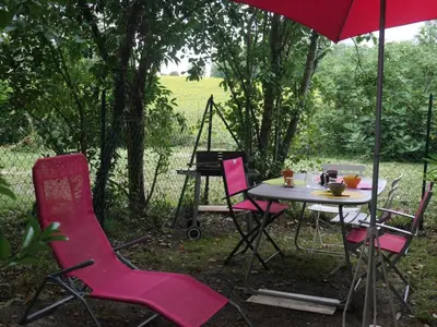 a table and chairs with an umbrella and a grill at Les platanes in Aignes