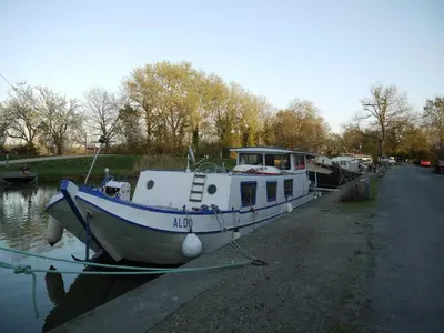 a boat is docked on the side of a canal at Les platanes in Aignes