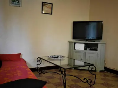 a living room with a tv and a glass table at Les platanes in Aignes