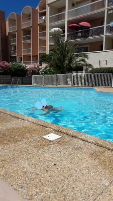 a person swimming in a swimming pool in a hotel pool at Plage du grazel le thalassa in Gruissan