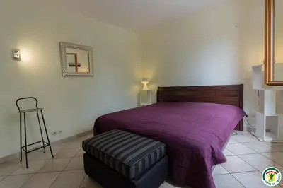 a bedroom with a bed with a purple blanket and a stool at La maison imart in Revel