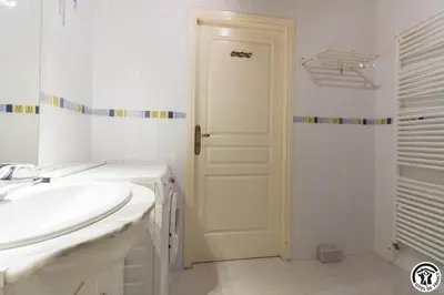a white bathroom with a sink and a door at La cajole in Montgaillard-Lauragais