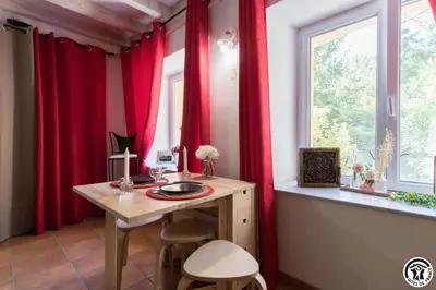 a room with red curtains and a table and a window at Gîte Domaine de la Fée de l'Eau – L'Eau d'Ô in Saint-Félix-Lauragais