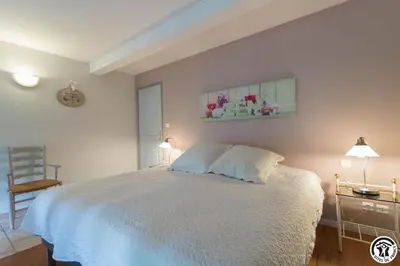 a bedroom with a white bed and a chair at Domaine de la fee de l'eau - les fees de l'o in Saint-Félix-Lauragais