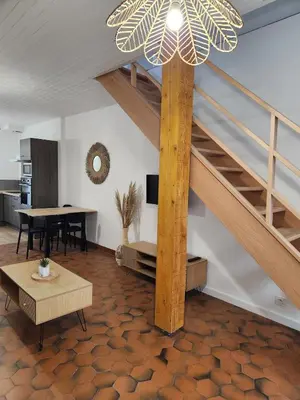 a living room with a staircase and a table at Appartement refait à neuf in Villeneuve-la-Comptal