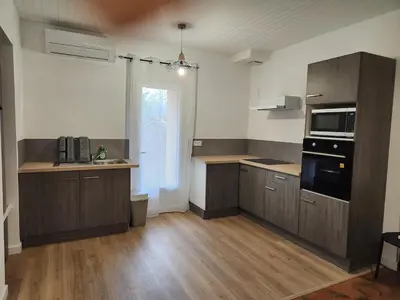 a large kitchen with wooden cabinets and a microwave at Appartement refait à neuf in Villeneuve-la-Comptal