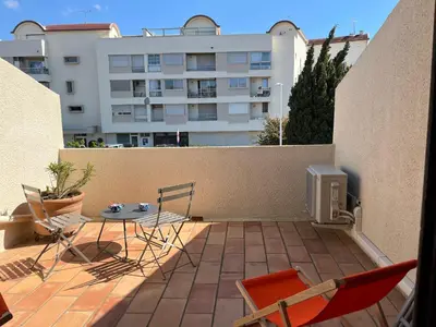 a patio with a table and chairs and a building at Villa Climatisée 6 Pers - Proche Port & Village - Parking Privé - FR-1-796-88 in Gruissan