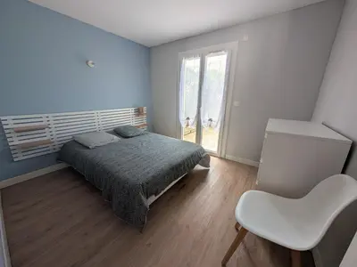 a bedroom with a bed and a chair and a window at Maison T5 110m² avec jardin clos, près de la plage, animaux acceptés, parking - FR-1-797-64 in Port-la-Nouvelle