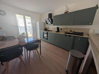 a kitchen with a table and chairs and a kitchen with green cabinets at Maison T5 110m² avec jardin clos, près de la plage, animaux acceptés, parking - FR-1-797-64 in Port-la-Nouvelle