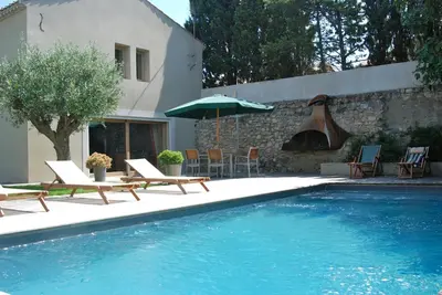 a swimming pool with chairs and an umbrella next to a house at Maison Standing - Exceptionnel in Roquefort-des-Corbières