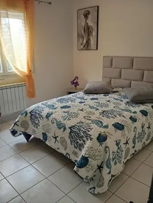 a bedroom with a bed with a blue and white comforter at Chez Lia in Rieux-Minervois