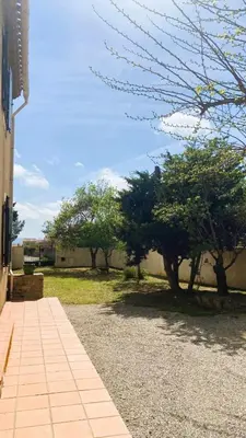 a walkway next to a building with trees in a yard at Maison Pagnol in Pépieux