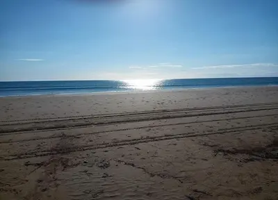 an empty beach with the sun shining on the ocean at Le Nova blue les pieds dans l'eau in Port-la-Nouvelle