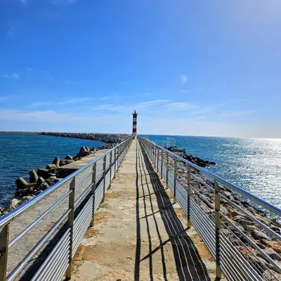 a lighthouse on a pier next to the ocean at Le Nova blue les pieds dans l'eau in Port-la-Nouvelle