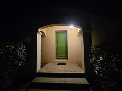 a green door on the side of a building at night at Logis de Gaia YourHostHelper in Homps