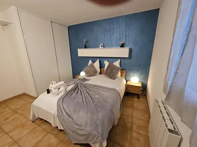 a bedroom with a bed with a blue wall at Logis de Gaia YourHostHelper in Homps