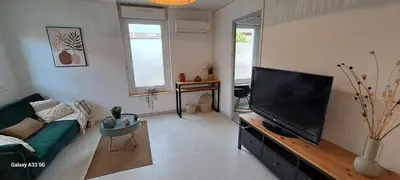 a living room with a green couch and a flat screen tv at Maison Calme au Centre du Village in Puisserguier