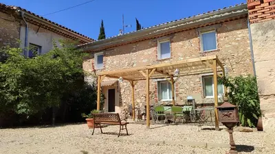 a stone building with a patio in front of it at Le gîte du moulin in Thézan-des-Corbières