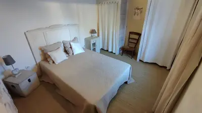 a bedroom with a large bed with white sheets and pillows at Le gîte du moulin in Thézan-des-Corbières