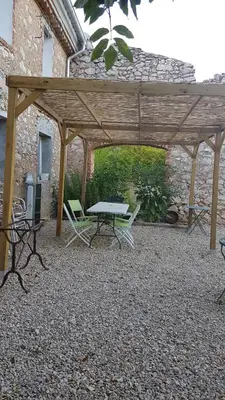 a picnic table and chairs under a wooden pergola at Le gîte du moulin in Thézan-des-Corbières