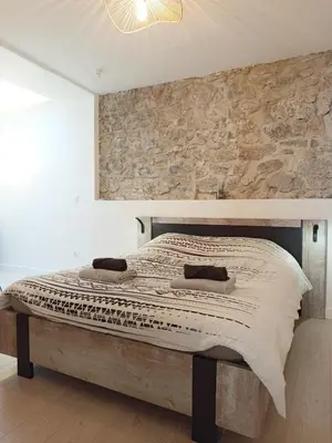 a bedroom with a bed with a stone wall at Kalipay - 7 min à pied des Grands Buffets in Narbonne