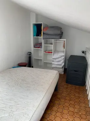 a bedroom with a bed and shelves of towels at Petite maisonnette de vacances in Gruissan