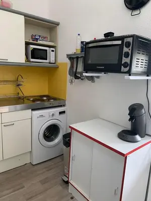 a kitchen with a washing machine and a microwave at Petite maisonnette de vacances in Gruissan