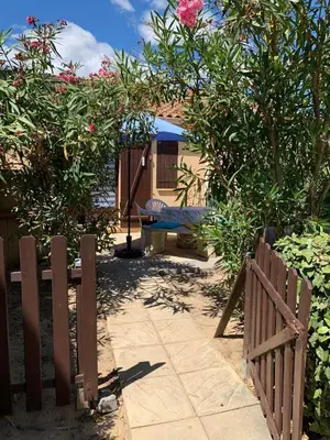 a wooden fence and a bench in a yard at Petite maisonnette de vacances in Gruissan