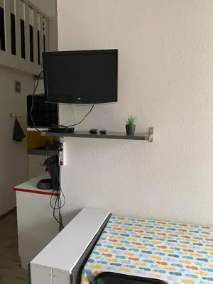 a room with a bed and a television on a wall at Petite maisonnette de vacances in Gruissan