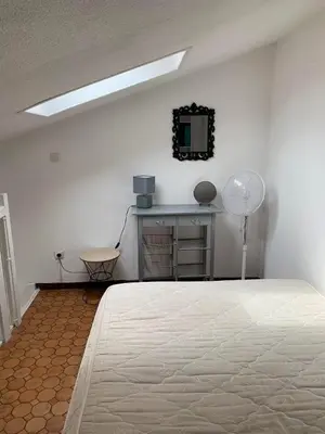 a white room with a bed and a mirror at Petite maisonnette de vacances in Gruissan