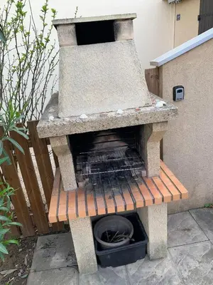 an outdoor grill sitting on a wooden bench at Petite maisonnette de vacances in Gruissan