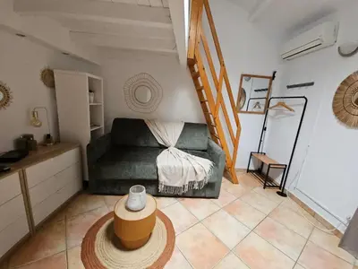 a living room with a green couch and a staircase at La Tiny House YourHostHelper in Narbonne