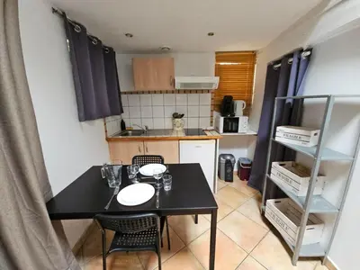 a small kitchen with a black table and chairs at La Tiny House YourHostHelper in Narbonne