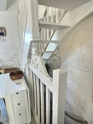 a white stairway with a white table and a stair case at Moulin du Sud in Lafage