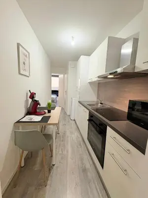 a kitchen with a small table and a kitchen with white cabinets at L'Écho du Castella in Pamiers