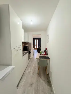 a kitchen with white walls and a table in a room at L'Écho du Castella in Pamiers