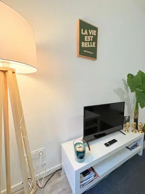 a living room with a tv on a white table at L'Écho du Castella in Pamiers