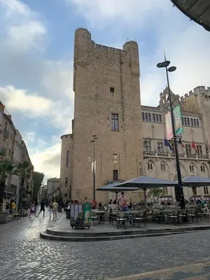 a building with tables and umbrellas in front of it at Maison de ville Centre de Narbonne 3 moulins in Narbonne