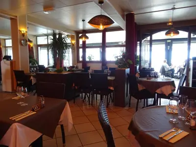 a restaurant with tables and chairs and people in the windows at Le Mazagan in Port-la-Nouvelle
