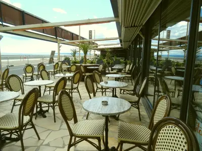 an empty restaurant with tables and chairs and the ocean at Le Mazagan in Port-la-Nouvelle