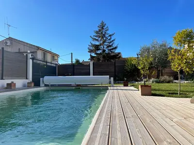 a swimming pool with a bench on a wooden deck at Villa avec piscine privée - Capestang in Capestang