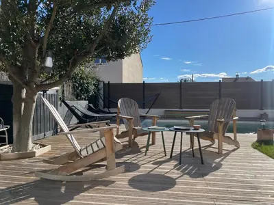 a patio with chairs and a table and a tree at Villa avec piscine privée - Capestang in Capestang