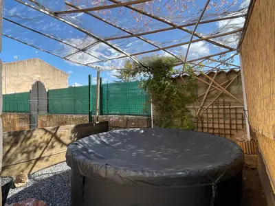 a covered patio with a round table in a building at Évasion ensoleillée avec jacuzzi à Cazedarnes in Cazedarnes