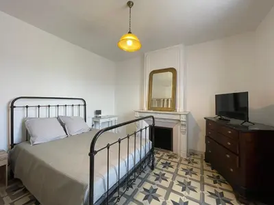 a bedroom with a bed and a television and a dresser at Évasion ensoleillée avec jacuzzi à Cazedarnes in Cazedarnes
