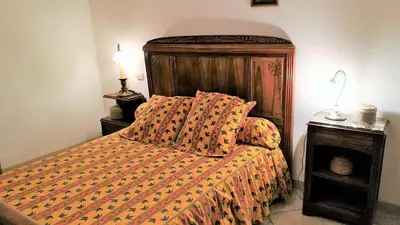 a bedroom with a bed with an orange comforter at La Maison Des Vendangeurs in Villesèque-des-Corbières