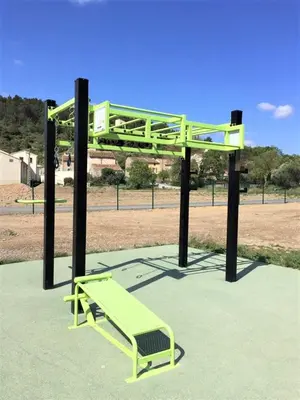 a green bench sitting on top of a park at La Maison Des Vendangeurs in Villesèque-des-Corbières