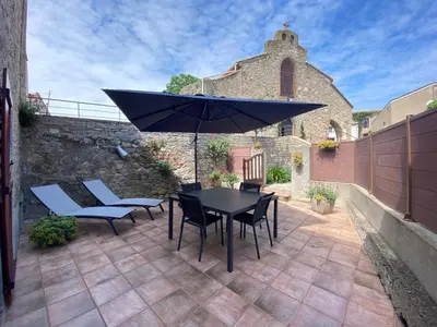 a patio with a table and chairs and an umbrella at La Maison Des Vendangeurs in Villesèque-des-Corbières