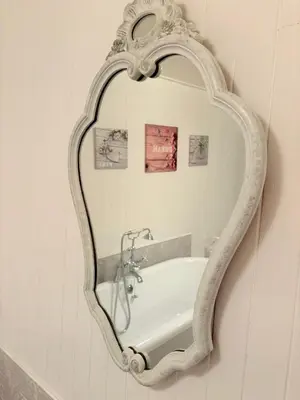 a mirror hanging on a wall with a bath tub at Las Coumeilles in Leychert